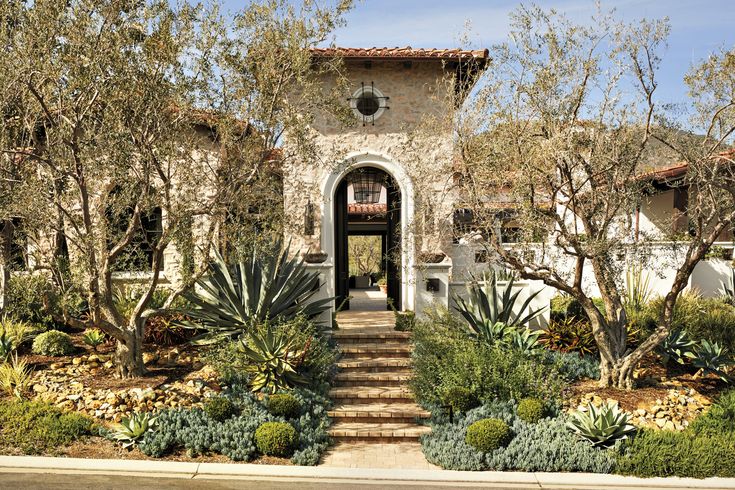 the front entrance to a house with trees and plants around it, along with steps leading up to an entry way