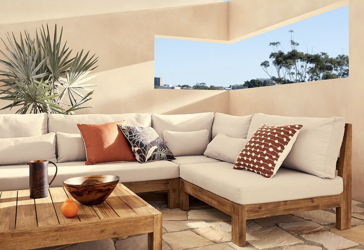 a couch with pillows on top of it next to a table and potted plant