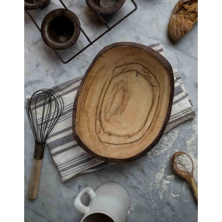 a wooden bowl sitting on top of a counter next to other kitchen utensils