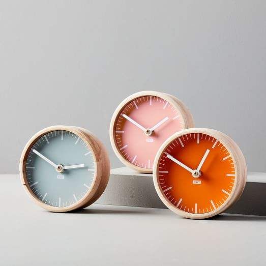 three clocks sitting on top of each other in front of a gray wall and floor