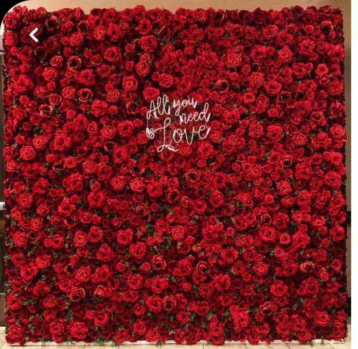 a large red flower wall with the words all you need is love written on it