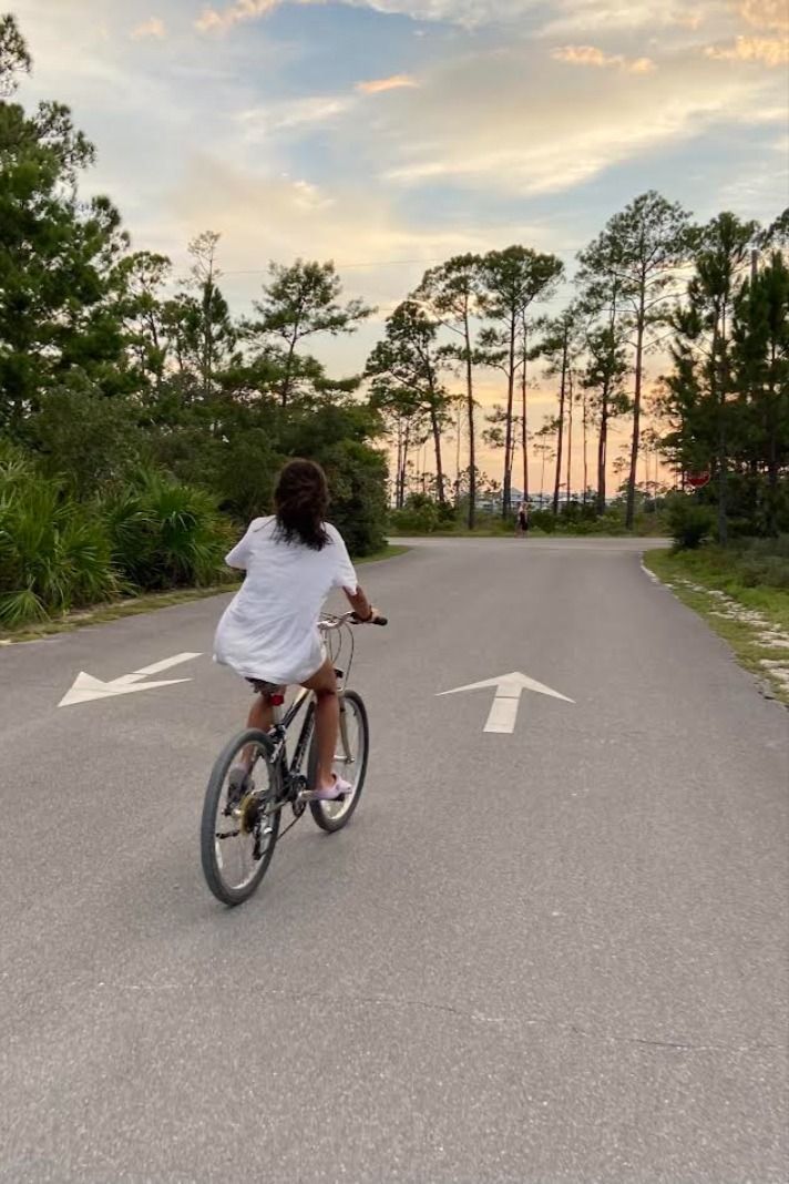 a person riding a bike down the middle of a road with trees in the background