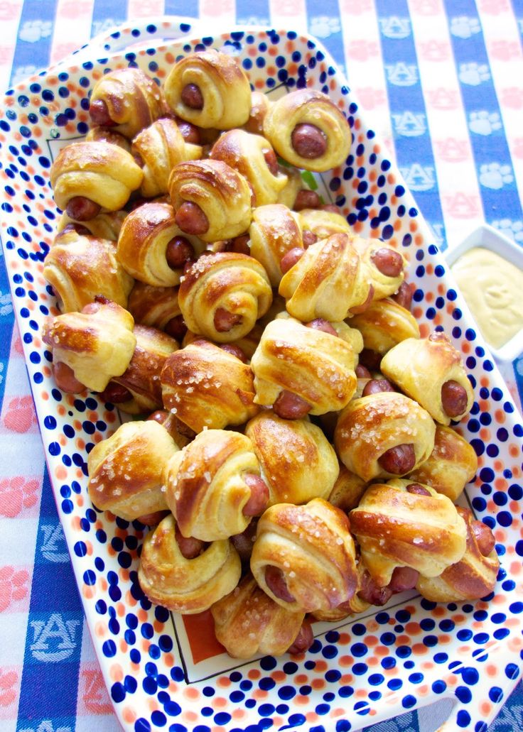 there is a plate full of pigs in a blanket on top of a blue and white table cloth