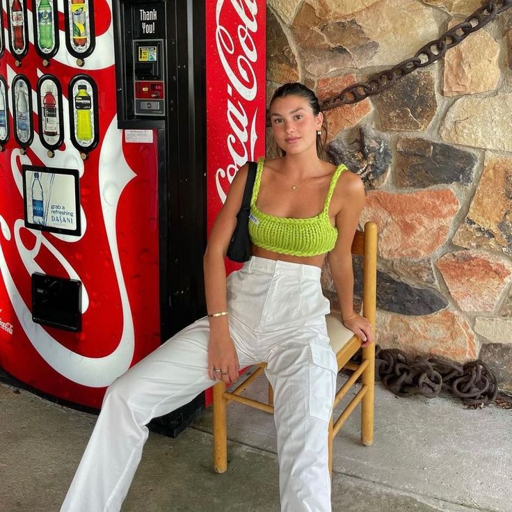 a woman sitting on a chair next to a coca - cola machine