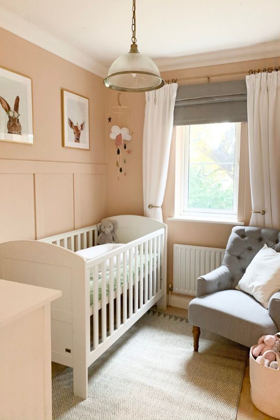 a baby's room with pink walls and white furniture