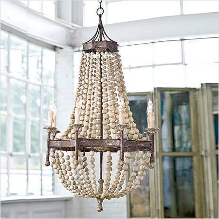 a wooden beaded chandelier hanging from a ceiling in a room with large windows