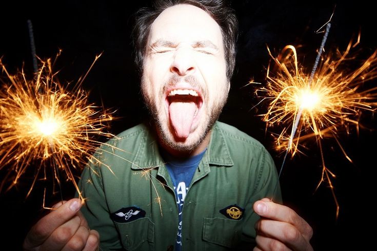 a man with his mouth open while holding two sparklers in front of his face