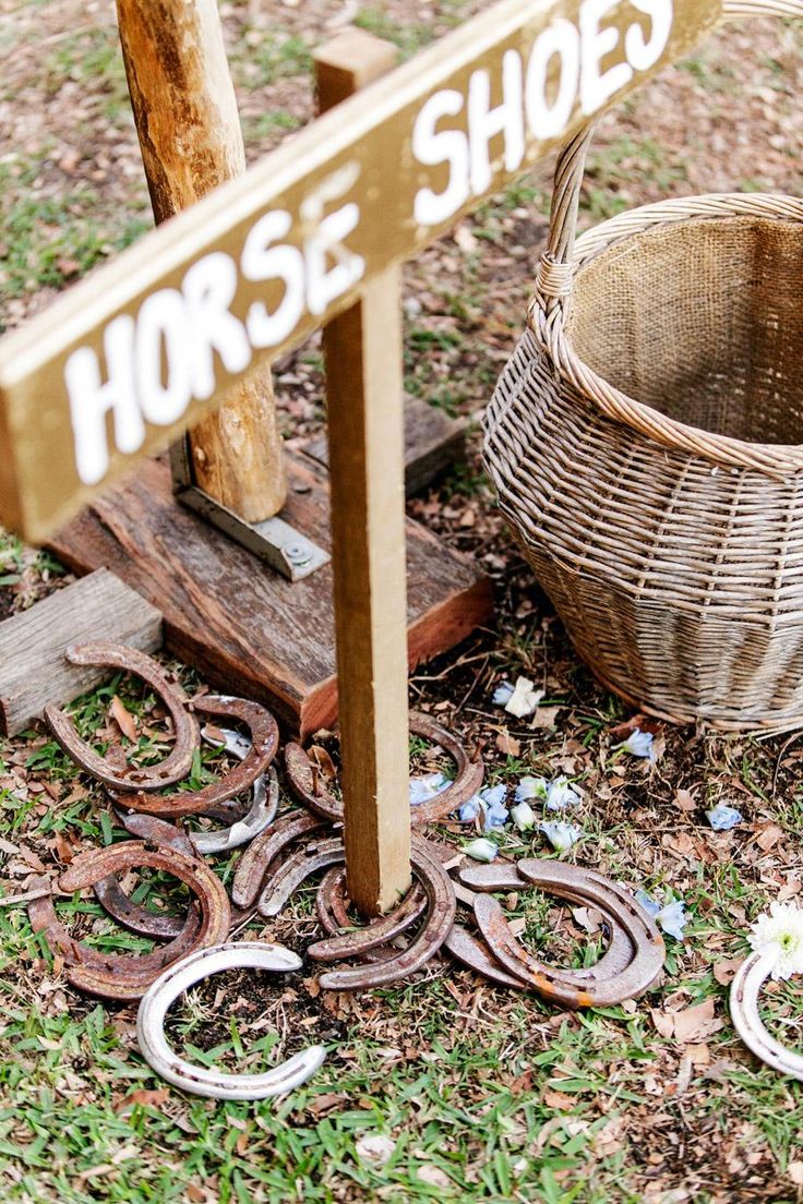 a horse shoe sign sitting on top of a wooden pole next to a basket filled with horseshoes