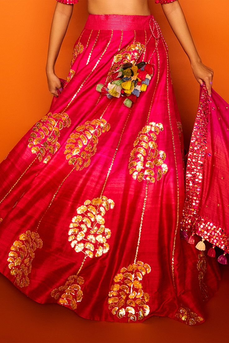 Fuchsia pink lehenga  hand embroidered with clusters of petals in gotapatti and sequined knots forming paisley motifs. Comes with cutwork blouse enhanced with mirrors, gotapatti, sequined knots and  ombre silk dupatta in shades of fuchsia and coral orange.
Components:3
Embroidered
Neckline:Round
Sleeve Length:Half
Fabric:Chanderi silk, raw silk, Tusser Silk
Color:Pink
Tassel dupatta
Pleated sleeve hem
Kamar latkans
Note: Red lehenga set worn by the model to the left is not for sale - Aza Fashion Pink Dola Silk Chandbali Lehenga, Pink Dori Work Chandbali Saree, Pink Raw Silk Traditional Wear For Navratri, Pink Semi-stitched Traditional Wear For Festival, Pink Kundan Lehenga For Navratri, Pink Embellished Lehenga For Navratri, Pink Raw Silk Lehenga For Navratri, Pink Lehenga With Dori Work In Art Silk, Pink Art Silk Lehenga With Dori Work