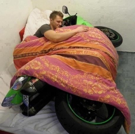 a man laying on top of a motorcycle covered in a blanket