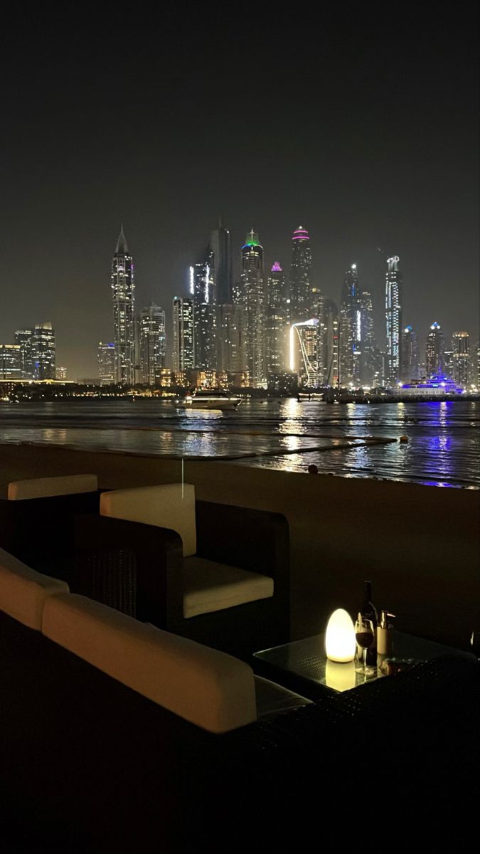 the city skyline is lit up at night with lights on tables and chairs in front of them