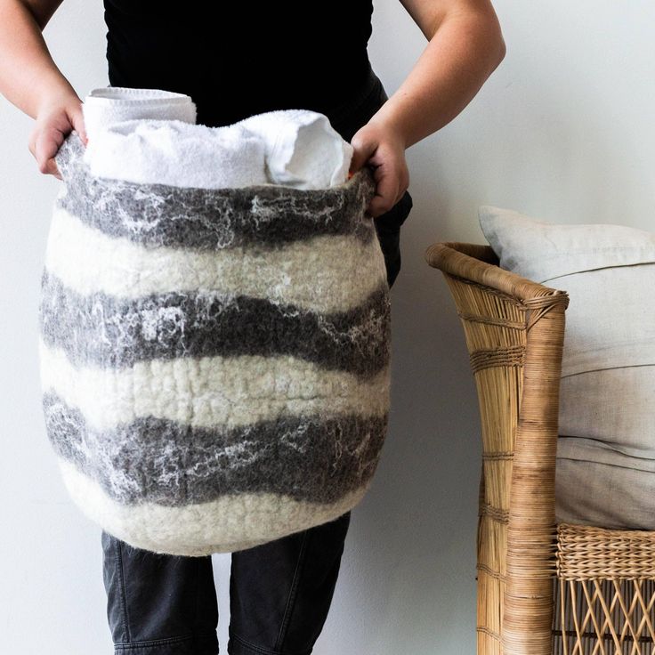 a woman is holding a large bag made out of sheep's wool, and standing next to a wicker basket