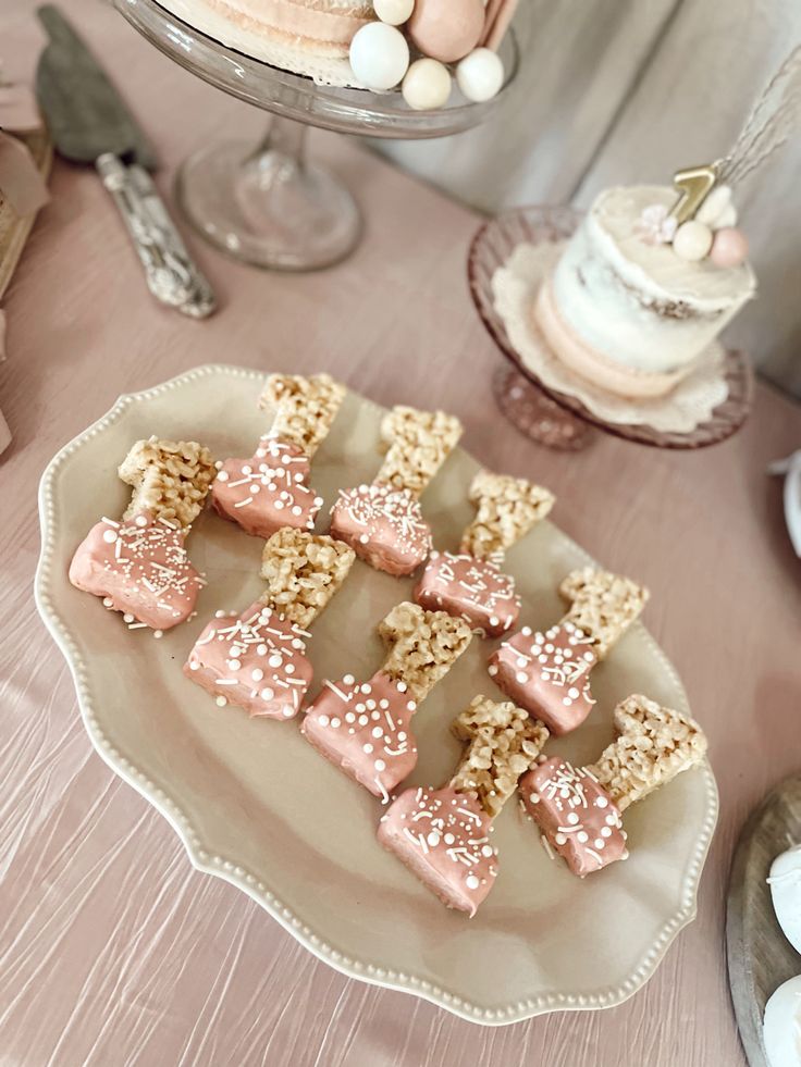 there are many desserts on the table with pink frosting and sprinkles