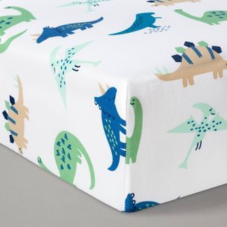 a close up of a bed sheet with dinosaurs on it and blue, green, yellow, and white colors