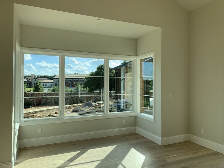 an empty room with large windows and hard wood flooring