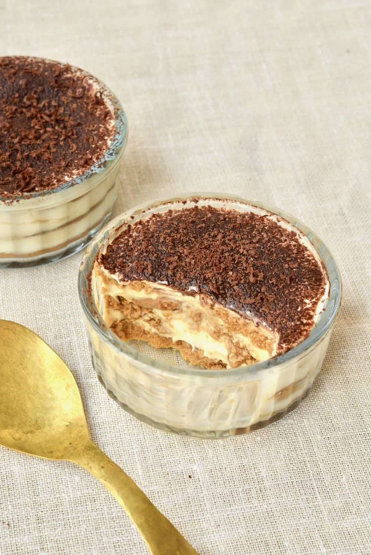 two desserts in glass dishes with gold spoons