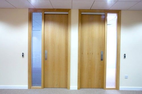 two wooden doors in an empty room with carpeted flooring and white walls on either side