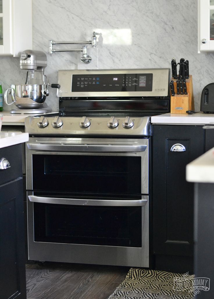 a stainless steel stove and oven in a kitchen with black cabinets, white counter tops and wood flooring