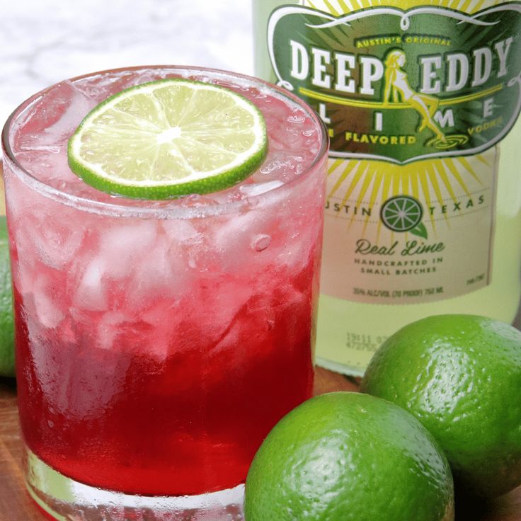 lime vodka and cranberry sparkler cocktail on a cutting board with limes