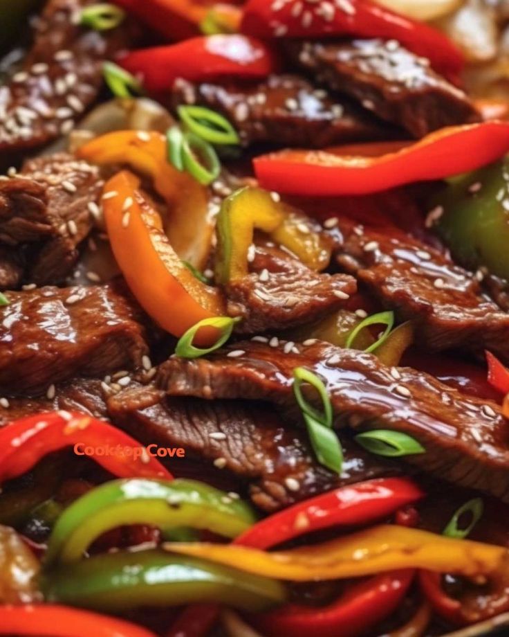 beef and peppers stir fry in a pan with sesame seeds on the side, ready to be eaten