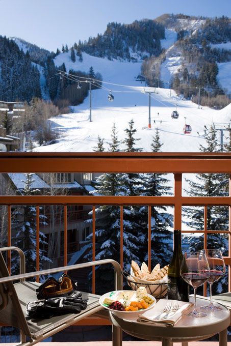 two chairs and a table with food on it in front of a snowy mountain view