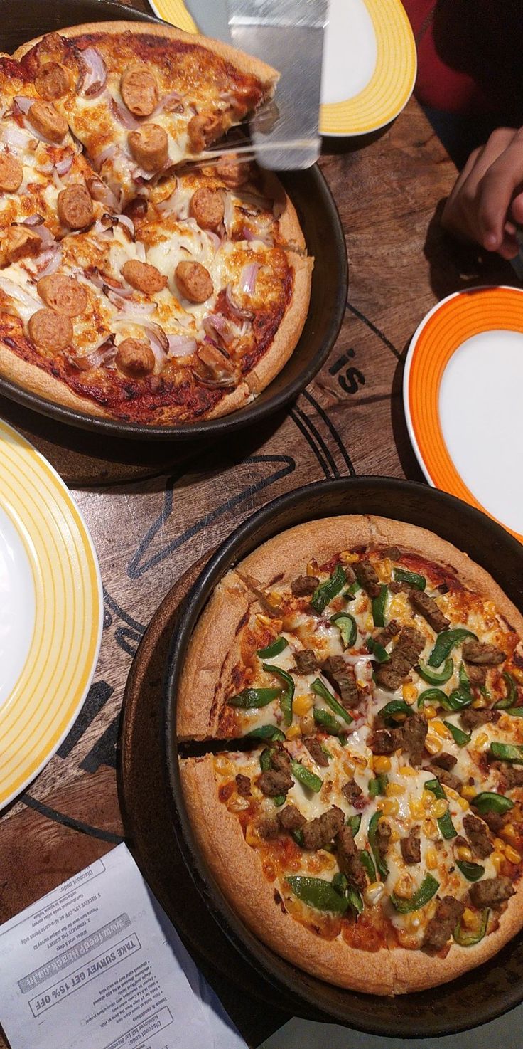 two pizzas sitting on top of pans with different toppings