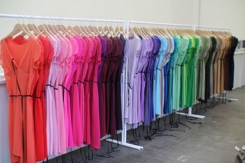 there are many different colored dresses hanging on the rack in front of each other at this store