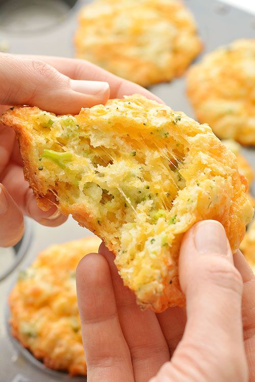 a person holding up a piece of food in their left hand and muffins on the other