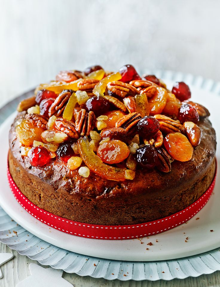 a cake with nuts and dried fruit on top sits on a plate, ready to be eaten