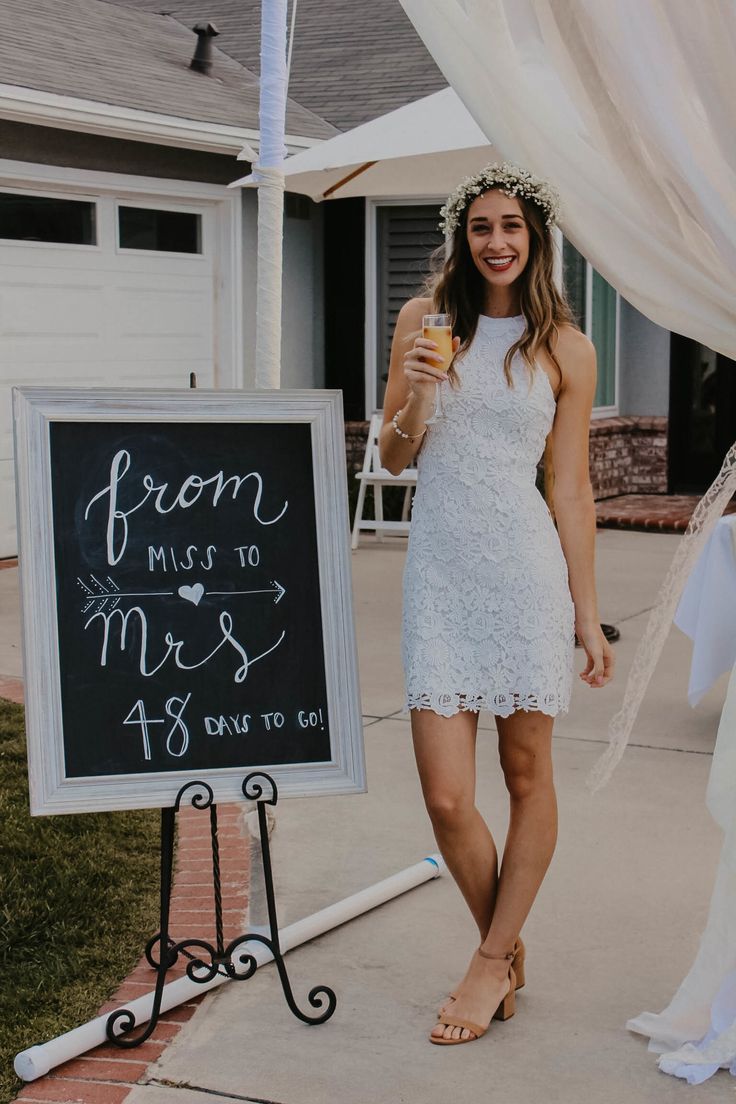 a woman standing in front of a sign holding a drink