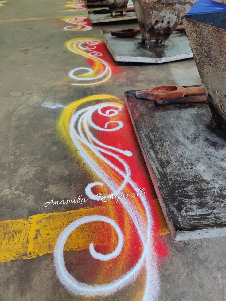 an artistic painting on the ground in front of some pots and pans with paint