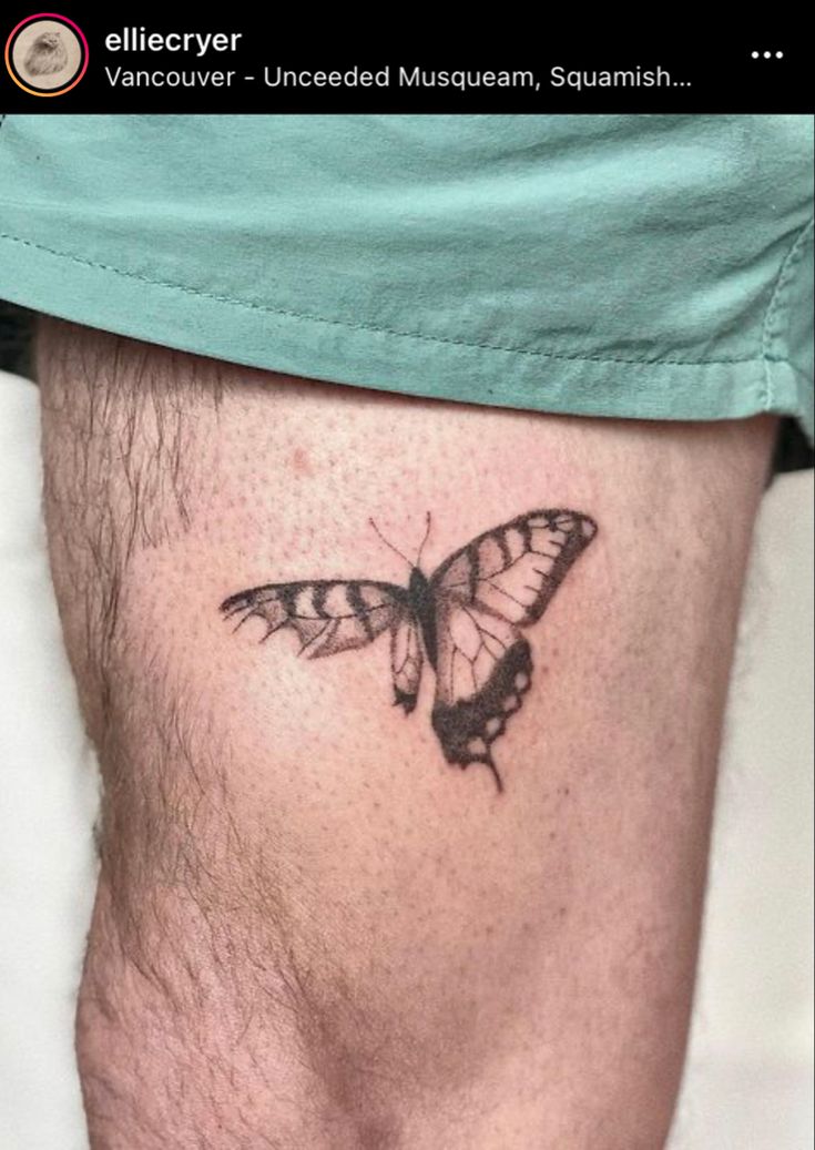 a small butterfly tattoo on the side of a man's lower leg, which is black and white