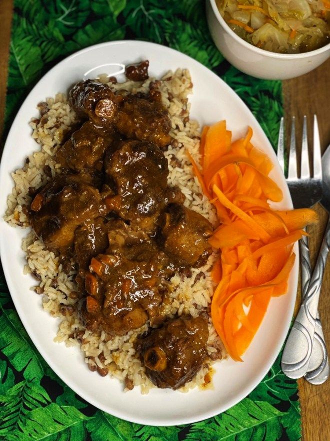 a white plate topped with meat and rice next to a bowl of carrot wedges