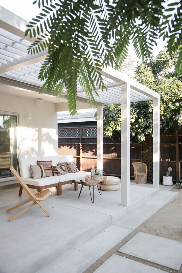 an outdoor living area with white furniture and plants