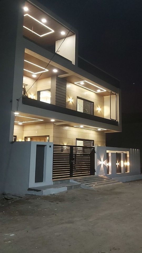 a house that is lit up at night with lights on the front and side of it