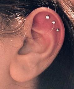 a woman's ear with three small white flowers on it