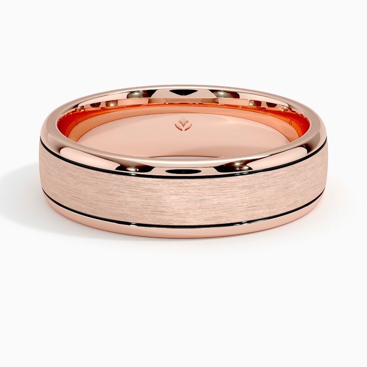 a rose gold wedding band with black dots on the side and an engraved design in the center