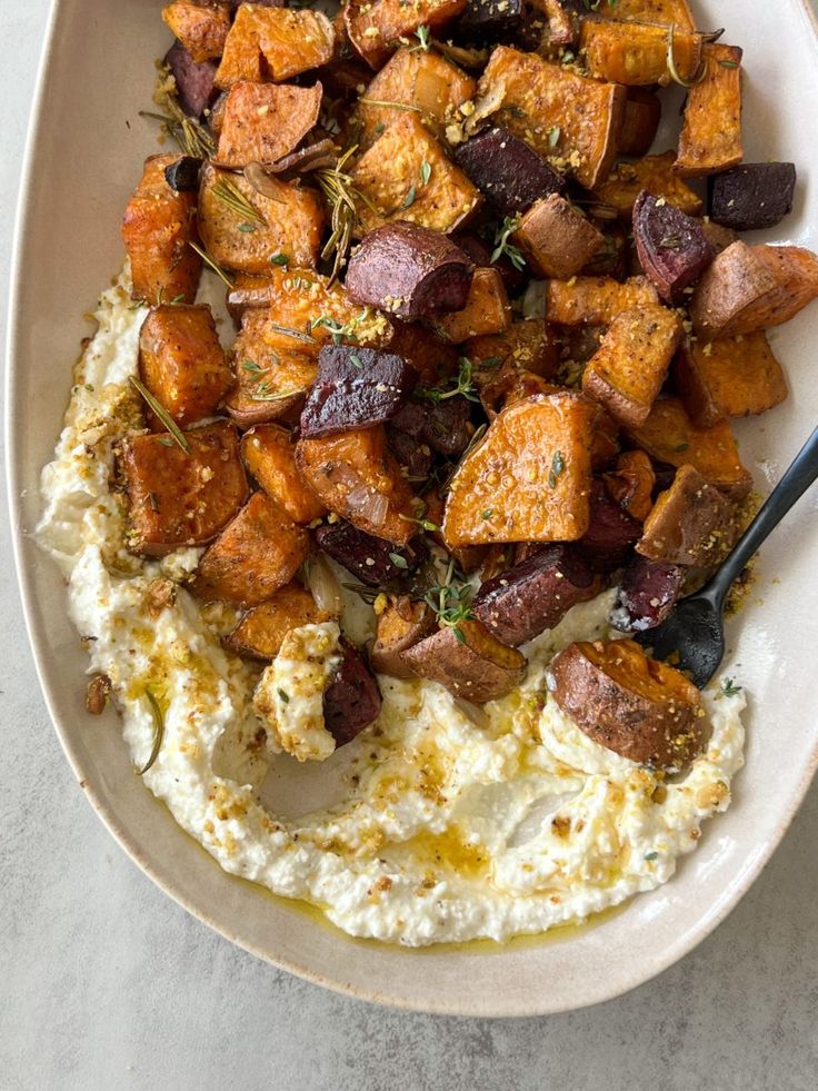 a bowl filled with potatoes and mashed potatoes on top of a white tablecloth