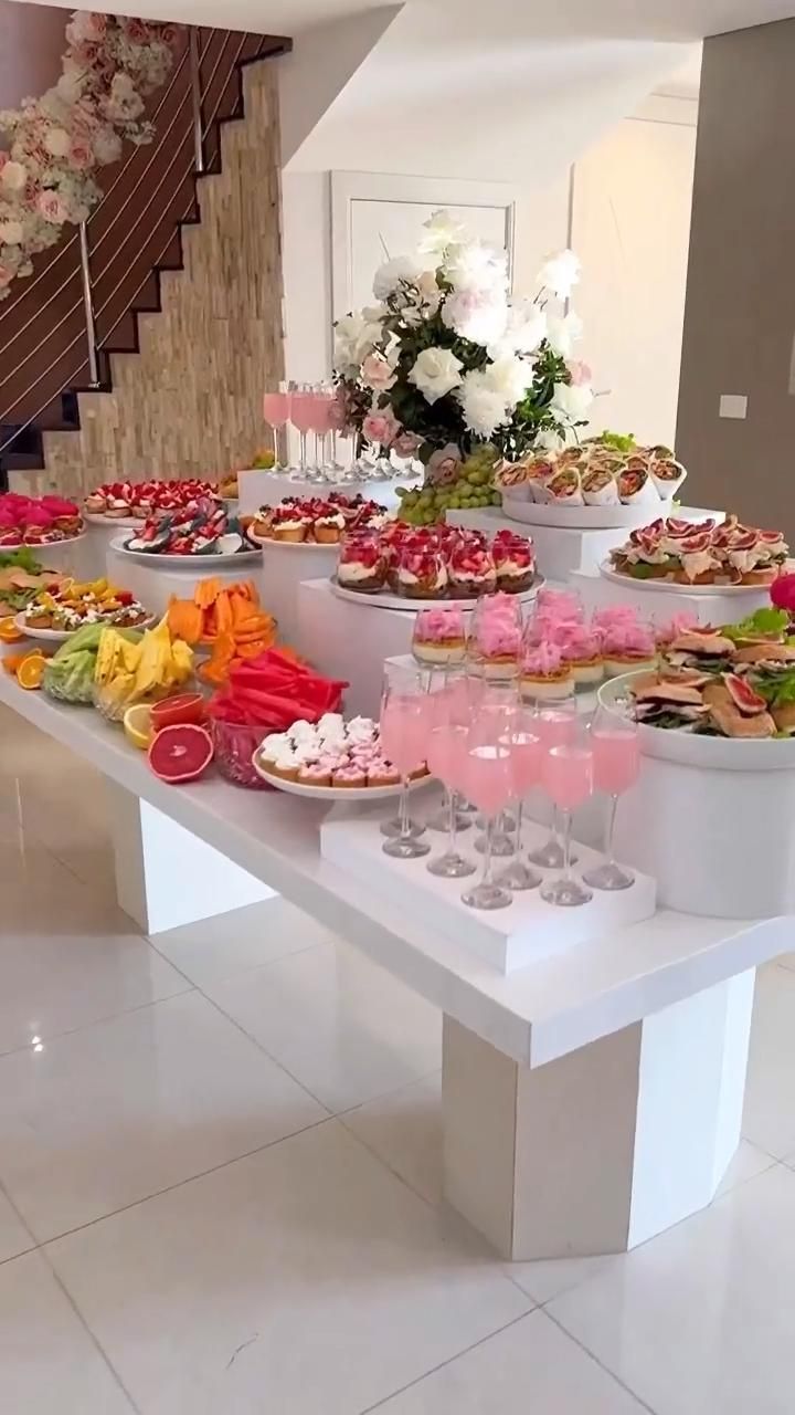 a table filled with lots of food on top of a white counter next to stairs