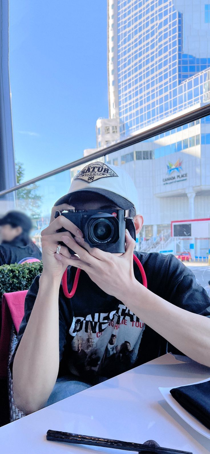 a man sitting at a table with a camera in front of his face, taking a photo