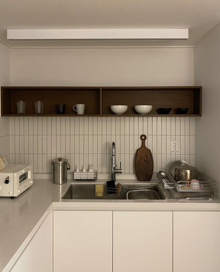 a kitchen with white cabinets and counter tops next to a microwave, toaster and dishwasher