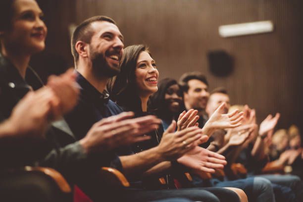 many people are clapping while sitting in chairs