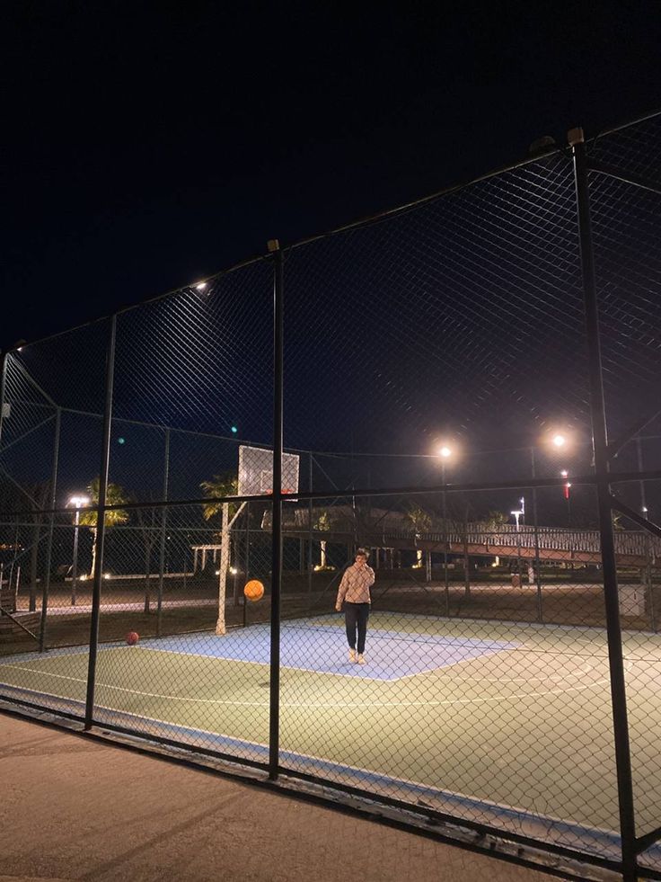 a person standing on a tennis court at night