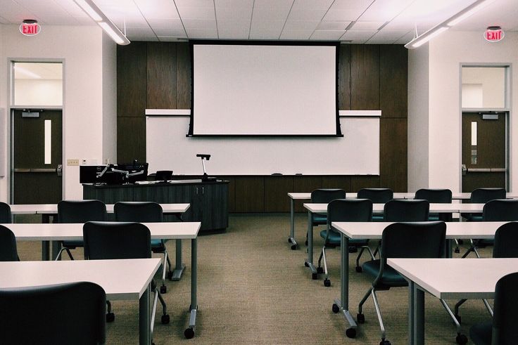 an empty classroom with desks and chairs in front of a projector screen that reads social media