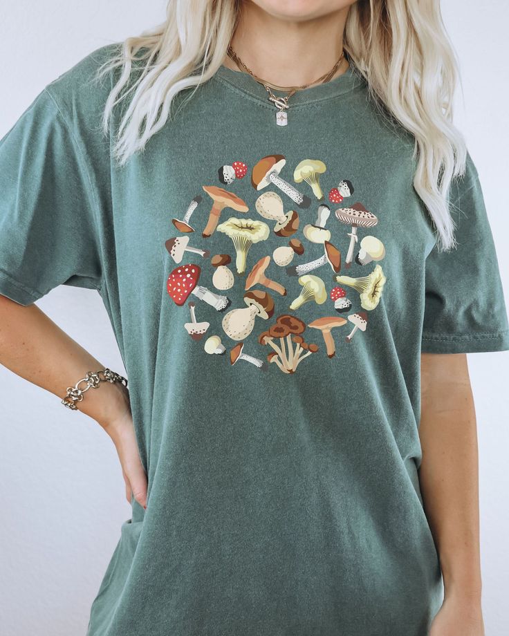 Looking for a unique and stylish gift? Look no further than our Comfort Colors Mushroom Shirt! This shirt features a vibrant mushroom design on the front. It's perfect for anyone who loves mushrooms, or just wants to show their love for nature in a fun and fashionable way. Whether you're giving it as a gift to your friend who loves mushrooms, or you're looking for something special to wear yourself, the Mushroom Shirt is sure to please. Comes in multiple colors! ✨️SIZE AND FIT: Your shirt will b Casual Mushroom Print T-shirt For Spring, Casual Cotton Tops With Mushroom Print, Casual Cotton Top With Mushroom Print, Summer Graphic Tee With Mushroom Print, Graphic Tee Shirt With Mushroom Print, Casual Green Tops With Mushroom Print, Relaxed Fit Fall Tops With Mushroom Print, Relaxed Fit Top With Mushroom Print For Fall, Relaxed Fit Mushroom Print Top For Fall