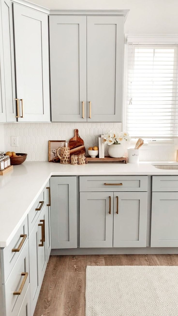 a kitchen with gray cabinets and white counter tops, gold hardware on the handles and pulls