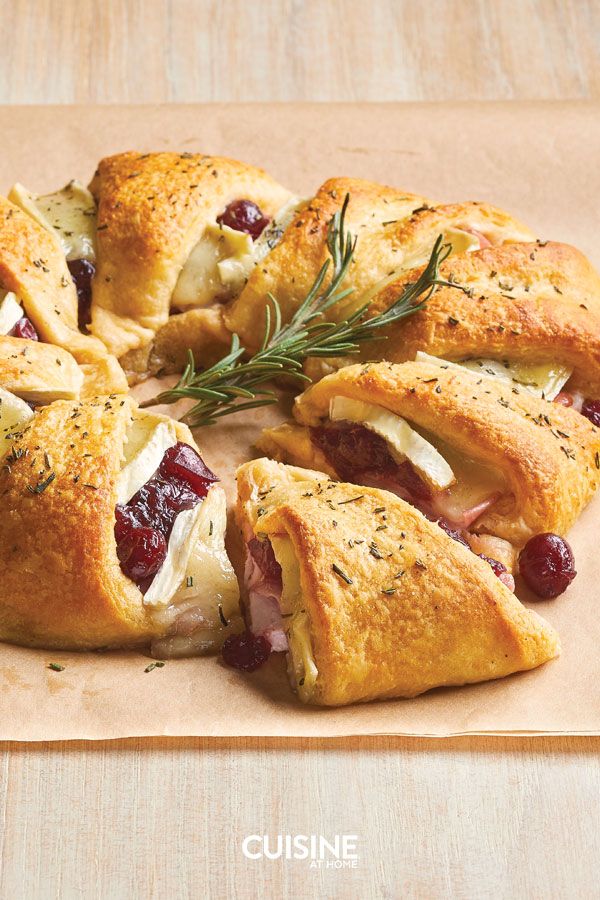 several pastries with meat, cheese and cranberry toppings on a cutting board