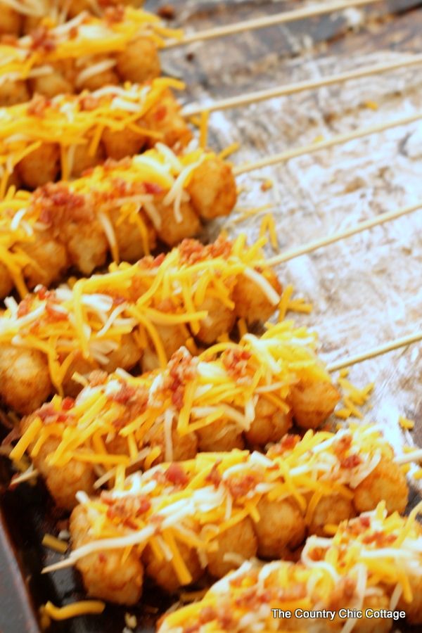 several skewers of food with cheese on them sitting on a baking sheet covered in wax paper