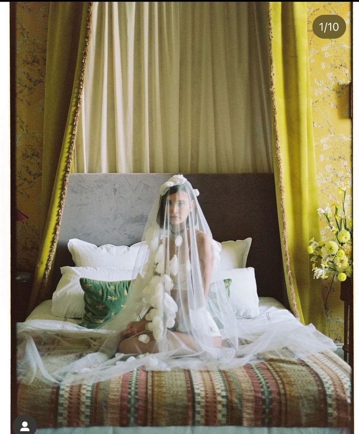 a woman sitting on top of a bed wearing a veil and holding a teddy bear