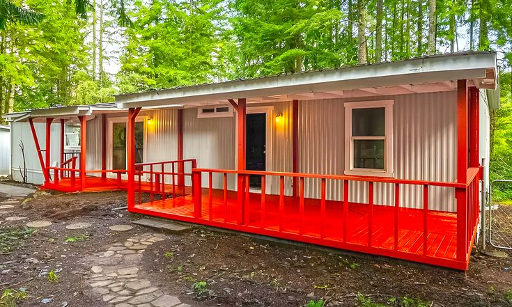 a small red and white cabin in the woods